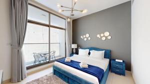 a bedroom with a blue bed and a large window at Primestay - Prime Views 1BR - Meydan in Dubai