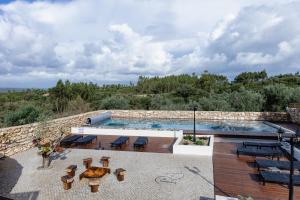 una piscina con mesas y sillas junto a una pared de piedra en Casa da Saia Grande - Recantos d'Almerinda, 