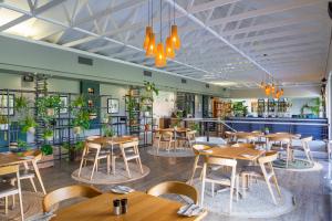 un restaurante con mesas de madera, sillas y plantas en Pearl Valley Hotel by Mantis, en Franschhoek