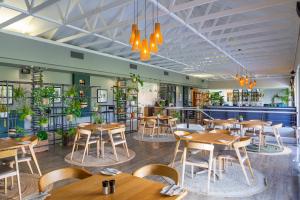 a restaurant with wooden tables and chairs and plants at Pearl Valley Hotel by Mantis in Franschhoek