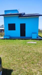 a blue house with a black door in a yard at Paraíso tropical in Balneário Gaivotas