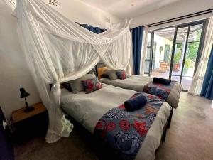 two beds in a bedroom with a canopy at Fawlty Towers Accommodation & Activities in Livingstone