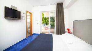 ein Hotelzimmer mit einem Bett und einem TV in der Unterkunft Hotel della baia - Negombo Parco Termale in Ischia
