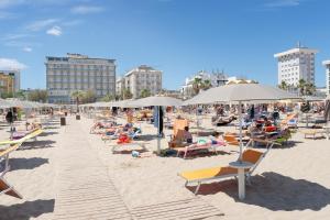 un gruppo di persone seduti su una spiaggia con ombrelloni di Hotel Centrale Miramare a Rimini