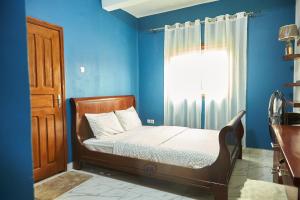 um quarto com uma cama com paredes azuis e uma janela em Résidence EKA Tonfack em Iaundé