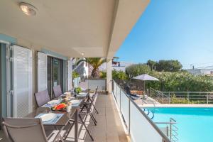 a balcony with tables and chairs next to a swimming pool at Bellavista 2 sea views in Alcudia