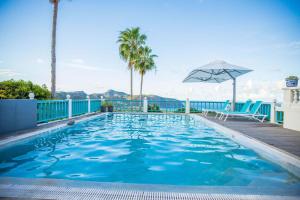 uma piscina com guarda-sol e palmeiras em Quill Gardens Boutique Hotel em Oranjestad