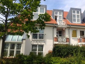 ein weißes Haus mit orangefarbenem Dach in der Unterkunft Bella Boltenhagen in Boltenhagen