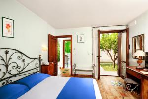 a bedroom with a bed and a desk and a door at Kallikoros Country Resort & Spa in Noto