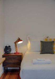 a bed with a clock and a lamp on a night stand at Apollo Bay House in Woodbridge