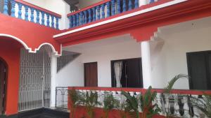 a house with red and white walls and blue stairs at INAS Guest House in Canacona