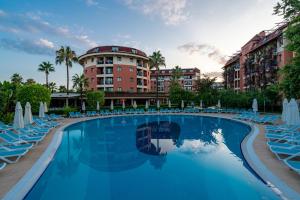 uma piscina com cadeiras e guarda-sóis em frente a um hotel em Palmeras Beach Hotel Ultra All Inclusive em Konaklı