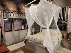 1 dormitorio con cama con dosel y mosquiteras en Lakeside Paradise Inhambane en Ligogo