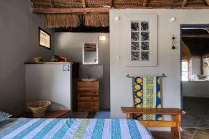 Lakeside Paradise Inhambane في Ligogo: غرفة بسرير وثلاجة وكرسي