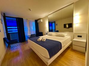 una camera da letto con un grande letto bianco e uno specchio di Orbi City Apartment Sea View a Batumi