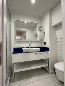 La salle de bains est pourvue d'un lavabo, d'un miroir et de toilettes. dans l'établissement Orbi City Apartment Sea View, à Batoumi