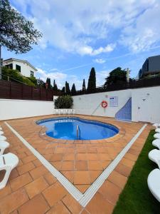 a swimming pool in a patio with white chairs at Hotel Turissa in Tossa de Mar