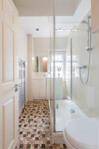 a bathroom with a shower and a toilet and a tub at Bond Street Apartment - Sleeps 4 in London