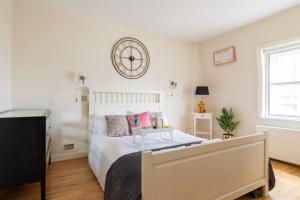 a bedroom with a bed and a clock on the wall at Bond Street Apartment - Sleeps 4 in London