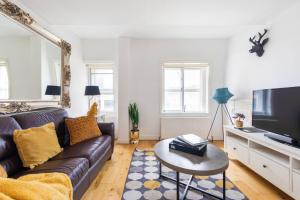 a living room with a couch and a tv at Bond Street Apartment - Sleeps 4 in London