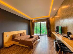 sypialnia z łóżkiem, telewizorem i oknem w obiekcie JK Riverview Resort w mieście Ban Song Phi Nong