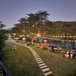 Ban Song Phi Nong的住宿－JK Riverview Resort，一群人坐在湖边的草上