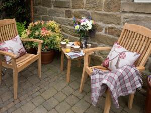 a patio with two chairs and a table with flowers at 1 Bed in Ripon G0127 in Kirkby Malzeard