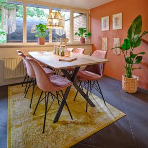 a dining room with a wooden table and pink chairs at Bungalow AMNIS in Lanaken