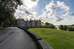 an old castle with a grassy field in front of it at Watermouth Castle, West Tower Apartment in Ilfracombe