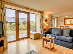 a living room with a blue couch and a sliding glass door at 3 Bed in Chideock DC087 in Chideock