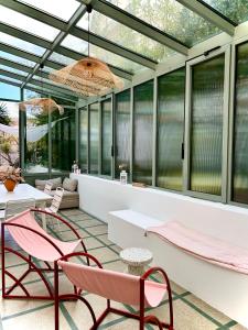 a glass conservatory with pink chairs and a table at MaïHomes - La Villa Marseillaise in Marseille