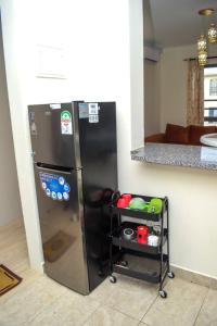einen Kühlschrank in einer Küche mit einem Wagen daneben in der Unterkunft Three Cozy Bedrooms at Palm Ridge in Vipingo