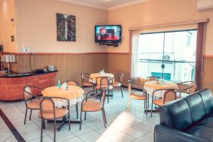 um restaurante com mesas e cadeiras e uma televisão na parede em STALO HOTEL em Piuí