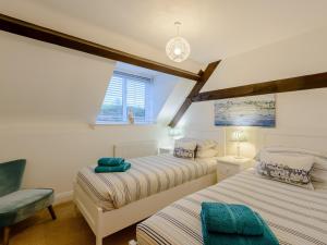 a bedroom with two beds and a chair at 2 Bed in Lulworth Cove DC028 in West Lulworth