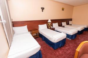 a hotel room with three beds and a table at فندق برج العالم in Mecca