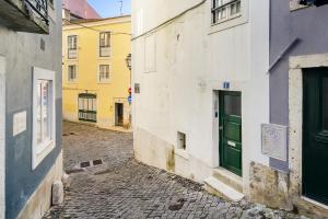 um beco com edifícios e uma porta verde em WHome Central Alfama Hideaway perfect to explore Lisbon em Lisboa