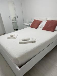 a white bed with two towels on top of it at PURA VIDA Beach Suite in Arguineguín
