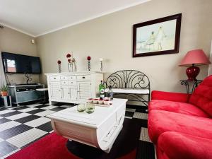 ein Wohnzimmer mit einem roten Sofa und einem Tisch in der Unterkunft Maison de famille au calme quartier de la Marcelliere in Les Sables-dʼOlonne