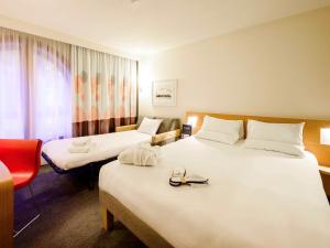Cette chambre d'hôtel comprend deux lits et un fauteuil rouge. dans l'établissement Novotel Birmingham Centre, à Birmingham