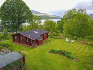 a small red house in a field with a yard at 2 Bed in Ardeonaig CA351 in Ardeonaig