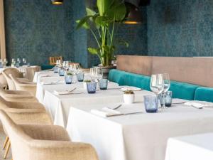 une rangée de tables dans un restaurant avec du linge de table blanc dans l'établissement Pullman Cannes Mandelieu Royal Casino, à Mandelieu-la-Napoule