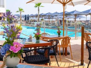 une terrasse avec des tables et des chaises ainsi qu'une piscine dans l'établissement Pullman Cannes Mandelieu Royal Casino, à Mandelieu-la-Napoule