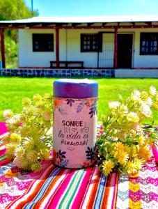 une tasse assise sur une table avec des fleurs dans l'établissement LA CABAÑA, à Termas de Río Hondo