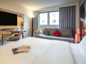 a hotel room with a couch and a tv at Novotel Wien City in Vienna