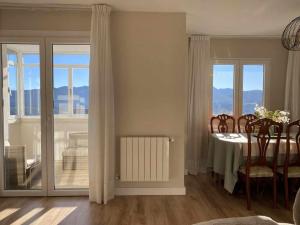 a living room with a table with chairs and windows at Mirador Solasierra montaña y pantano VUT-LE-5623 in Riaño