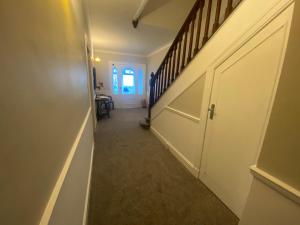 a hallway with a white door and a stair case at Amazing views across the Moray Firth, Private Suntrap Patio, 300m from the Beach, off street parking! in Nairn