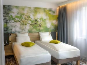 twee bedden in een kamer met een schilderij aan de muur bij Novotel Suites Wien City Donau in Wenen