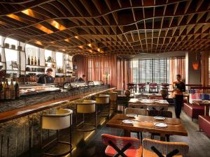 VIE Hotel Bangkok, MGallery في بانكوك: مطعم مع بار مع الكراسي والطاولات