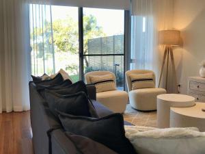 a living room with a couch and chairs and windows at Pullman Magenta Shores Resort in The Entrance