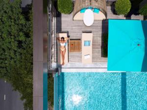 an overhead view of a woman standing next to a swimming pool at VIE Hotel Bangkok, MGallery in Bangkok
